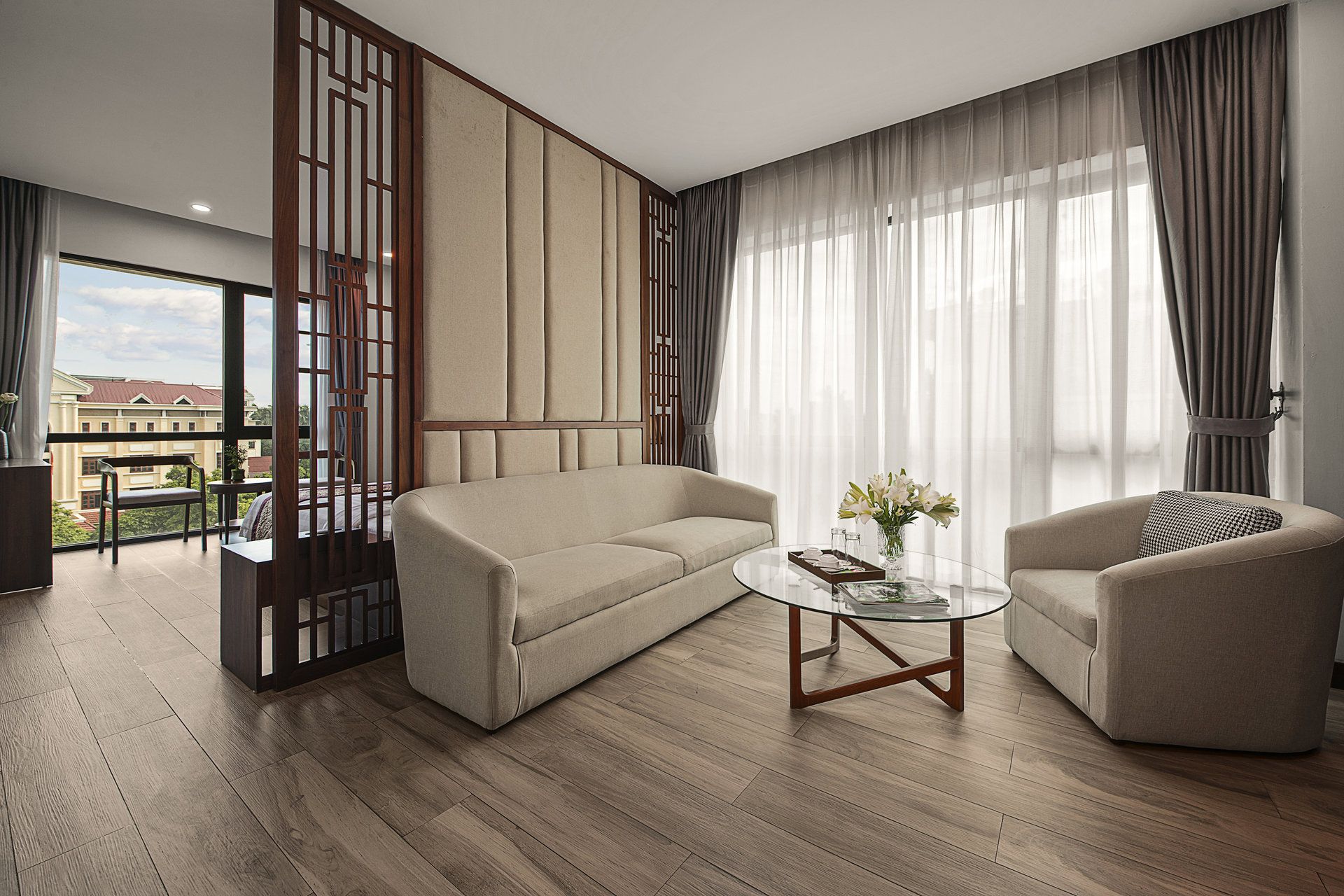 A modern living room with a sofa, armchair, and a glass coffee table.