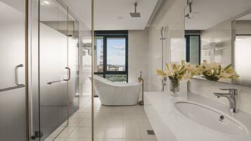 A modern bathroom with a freestanding bathtub, a large mirror, and a window offering a city view.