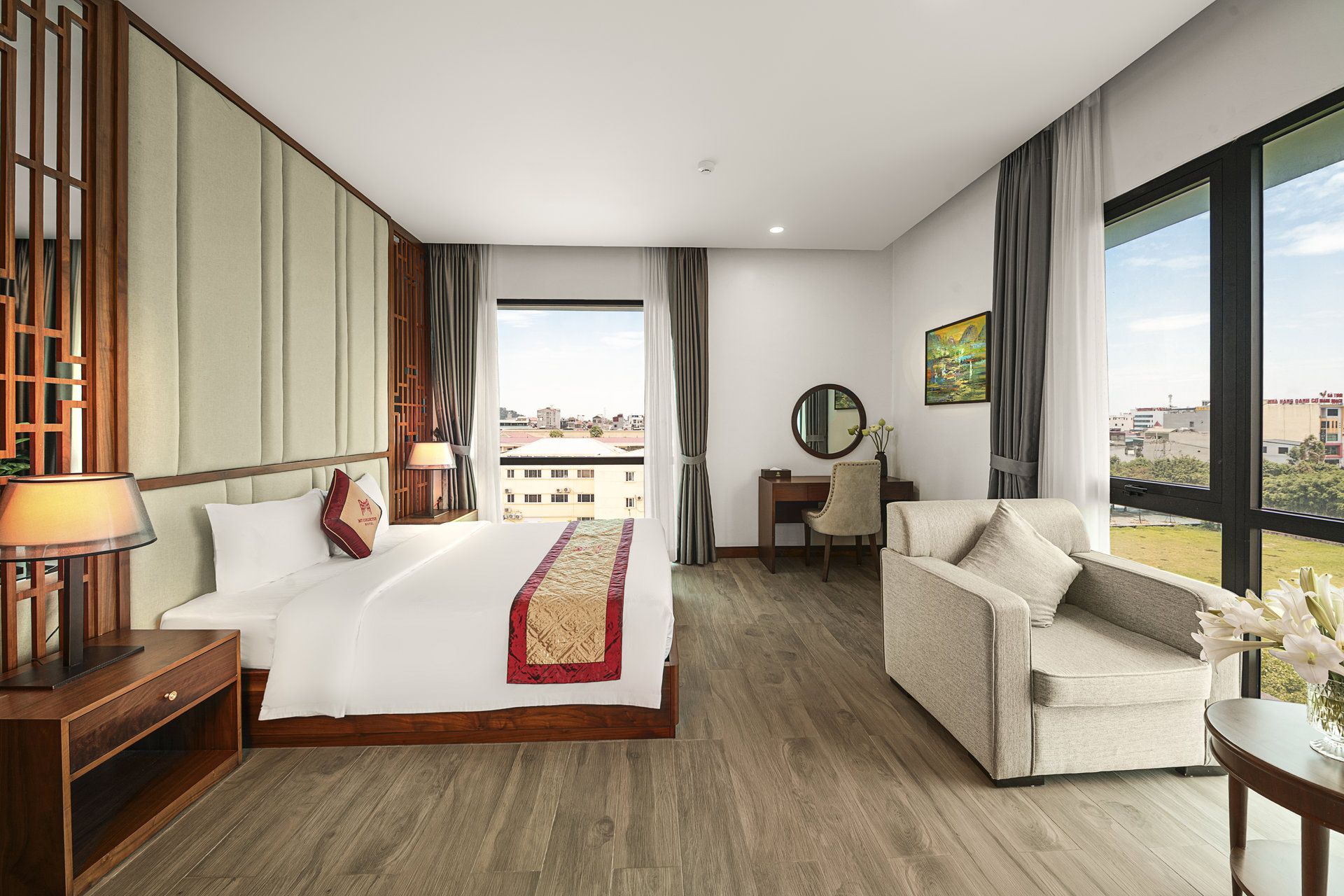 Een hotelkamer met een groot bed, een bureau, een stoel en uitzicht op de stad.