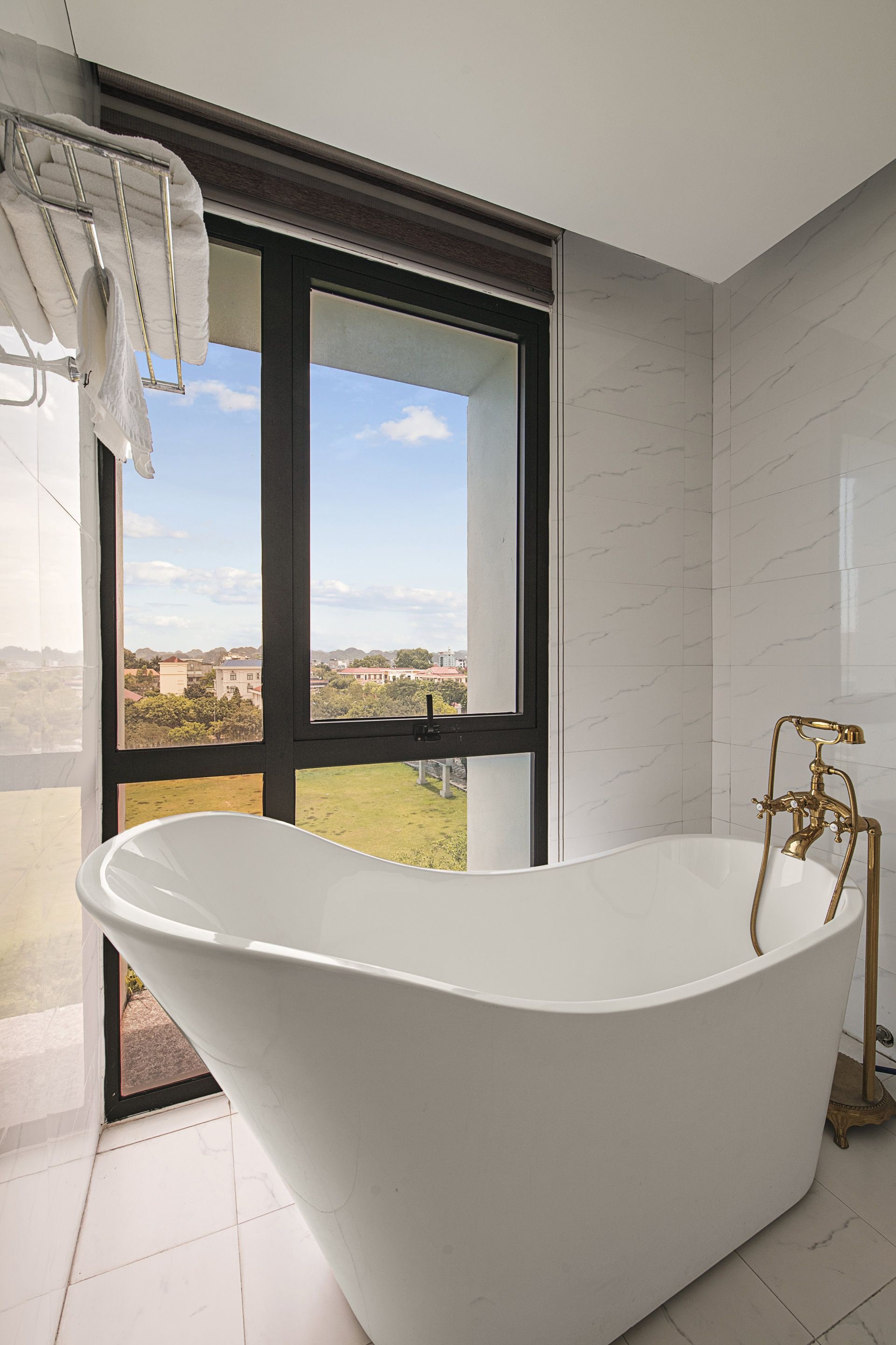 A modern bathroom with a freestanding bathtub, a large window, and a view of the outdoors.