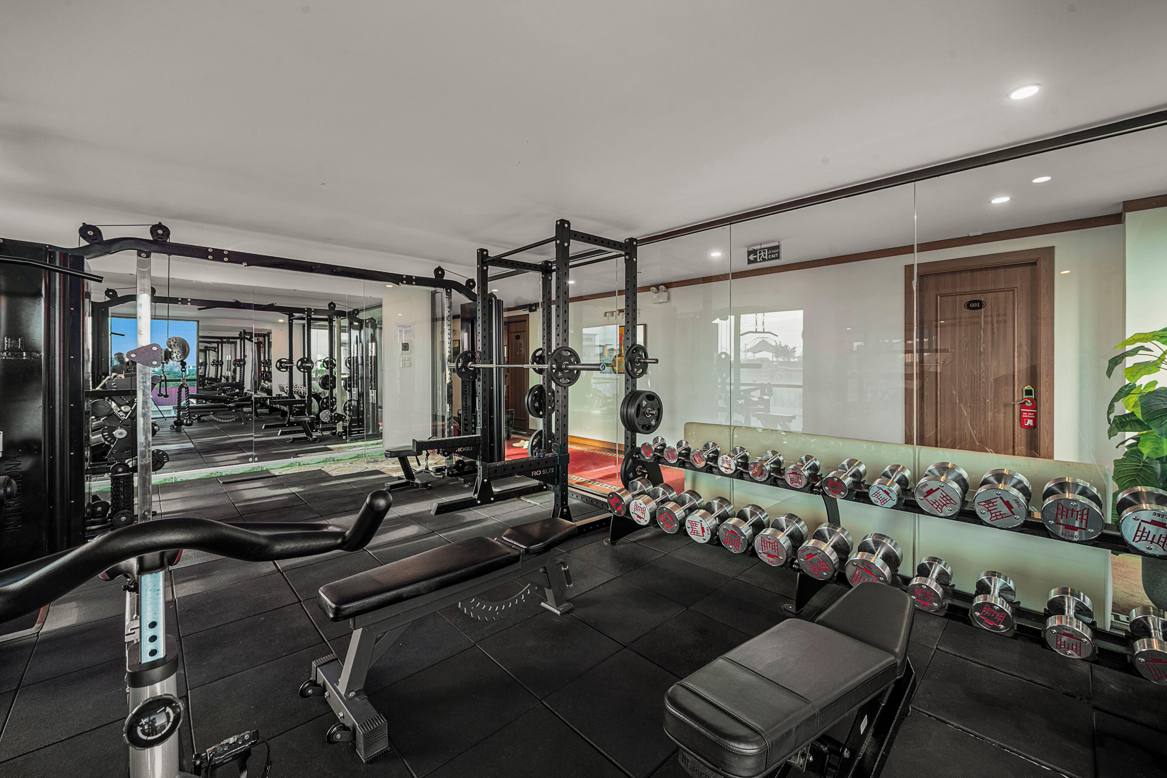 A gym with weightlifting equipment, benches, and dumbbells.