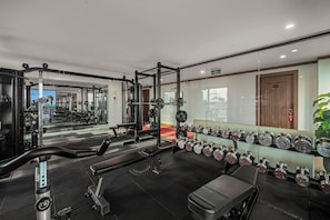 Uma academia com equipamentos de musculação, bancos e halteres.