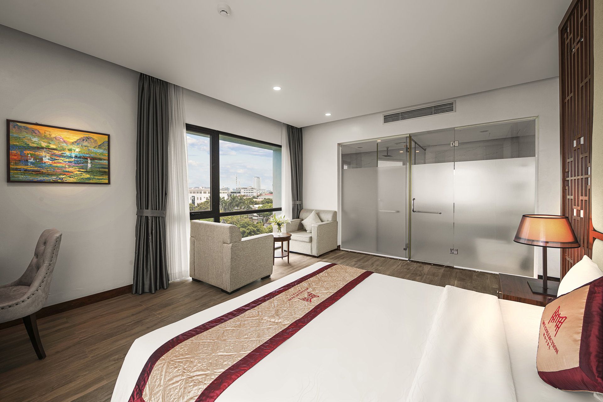 A hotel room with a bed, a chair, a desk, a wardrobe, and a view of the city.