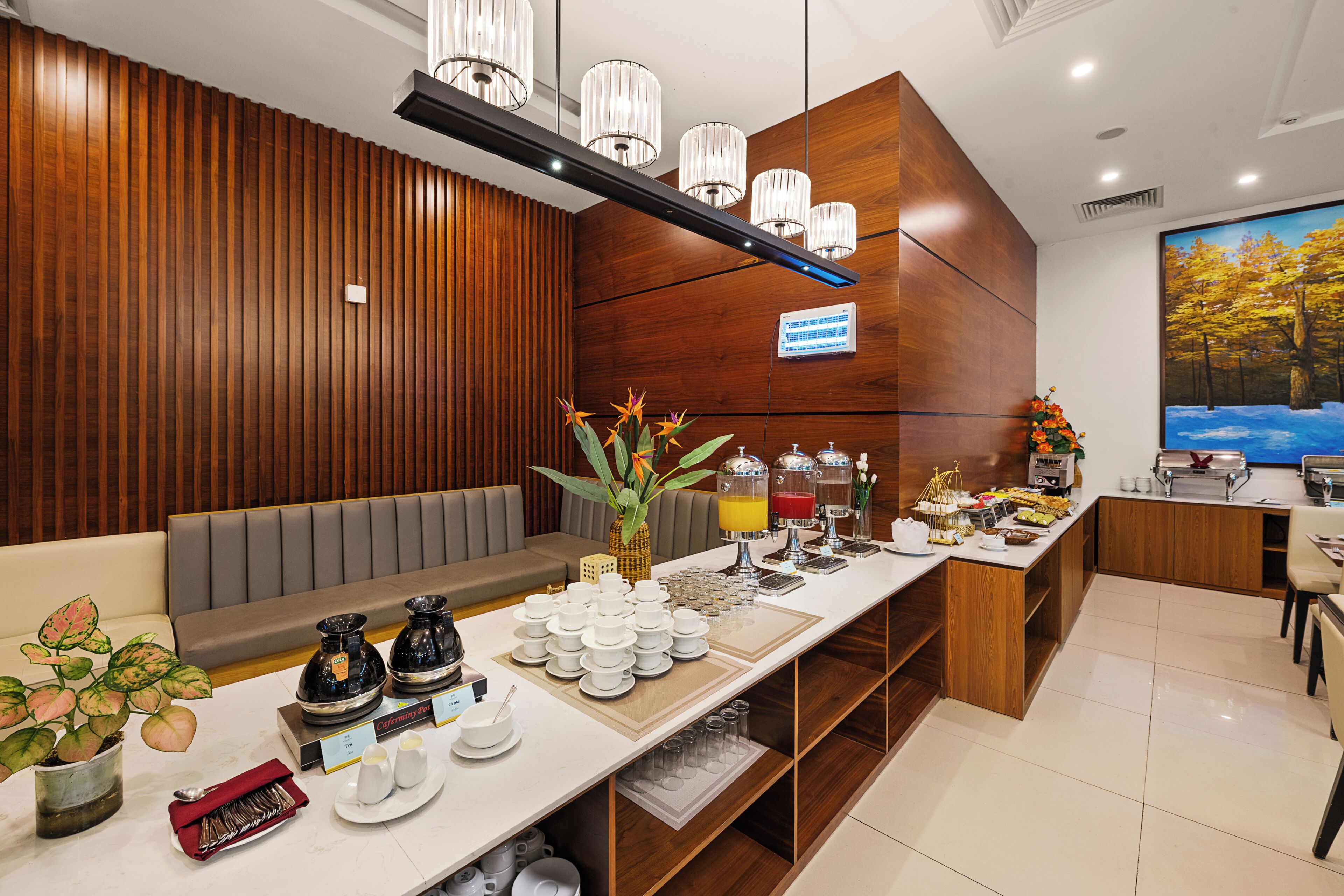 A hotel reception area with a long counter, a seating area, and a painting on the wall.