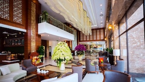 A spacious lobby with a high ceiling, a seating area with sofas and armchairs, a large floral centerpiece, and a view of the hotel's interior. - MT Collection Hotel (Hoa Lu)
