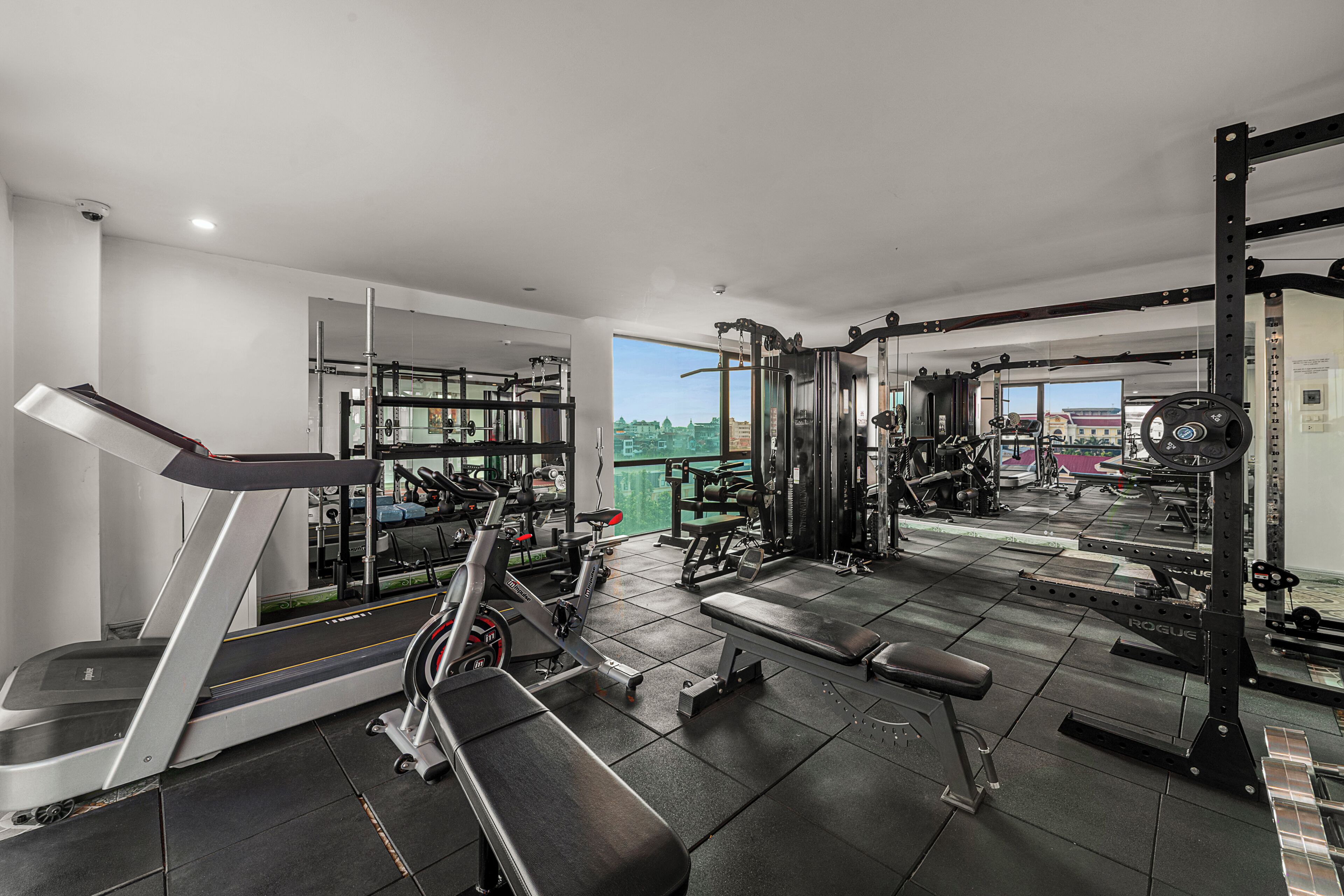 Un gimnasio moderno con cinta de correr, banca para pesas y equipamiento de levantamiento de pesas.