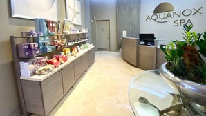A reception area with a counter displaying various products, a reception desk, and a wall-mounted sign for Aquanox Spa.