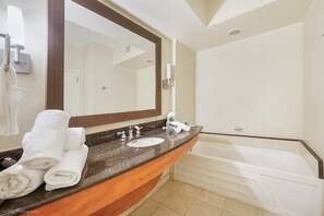 A modern bathroom with a granite countertop, a large mirror, a bathtub, and a towel rack with folded towels. - Elegant Resort Studio with Breathtaking Views (Sunny Isles Beach)