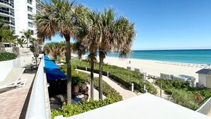 A beachfront hotel with a pool area, palm trees, and a view of the beach and ocean.