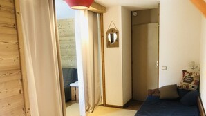 A cozy room with a bed, a chair, and a small table. - La Clairière 1 - Cosy studio with a beautiful view of the resort (LES AVANCHERS VALMOREL)