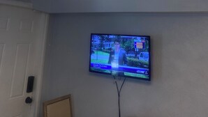 Una habitación con una lámpara en el techo, un televisor en la pared y una puerta.