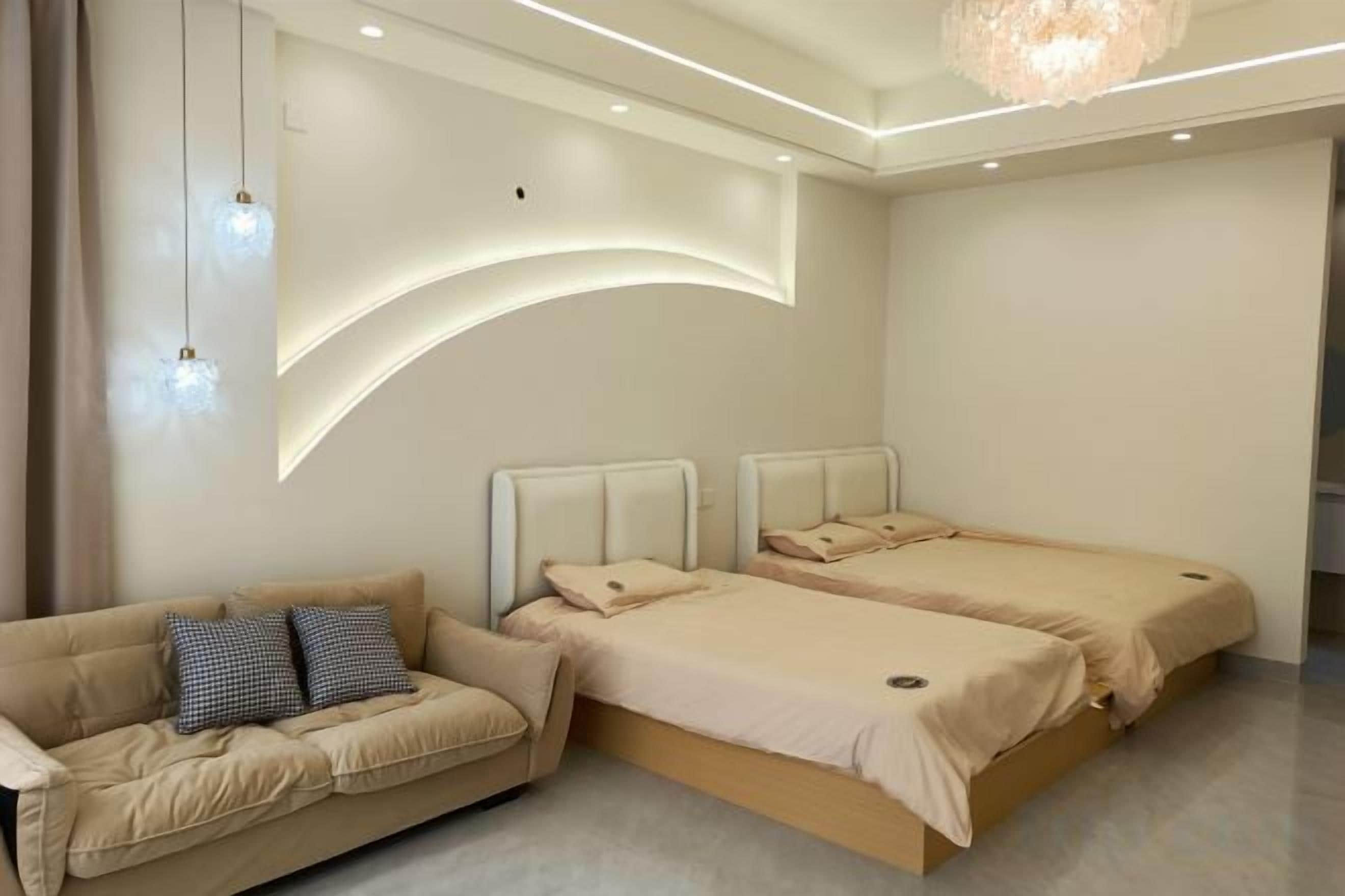 Ein Schlafzimmer mit zwei Betten, einem Sofa und einer Kristallleuchter.