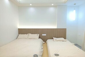Ein Hotelzimmer mit zwei Betten, einem modernen Kopfteil und einem Oberlicht.