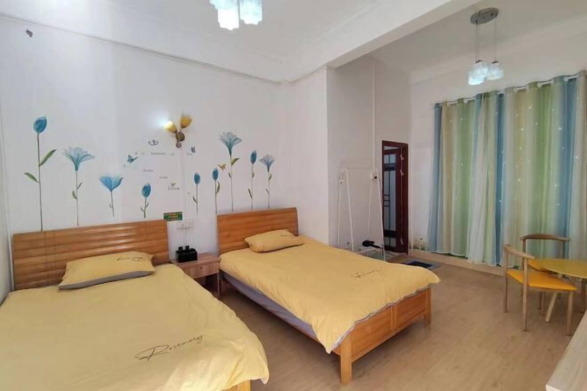 A hotel room with two beds, a wooden headboard, a small table, and a chair.