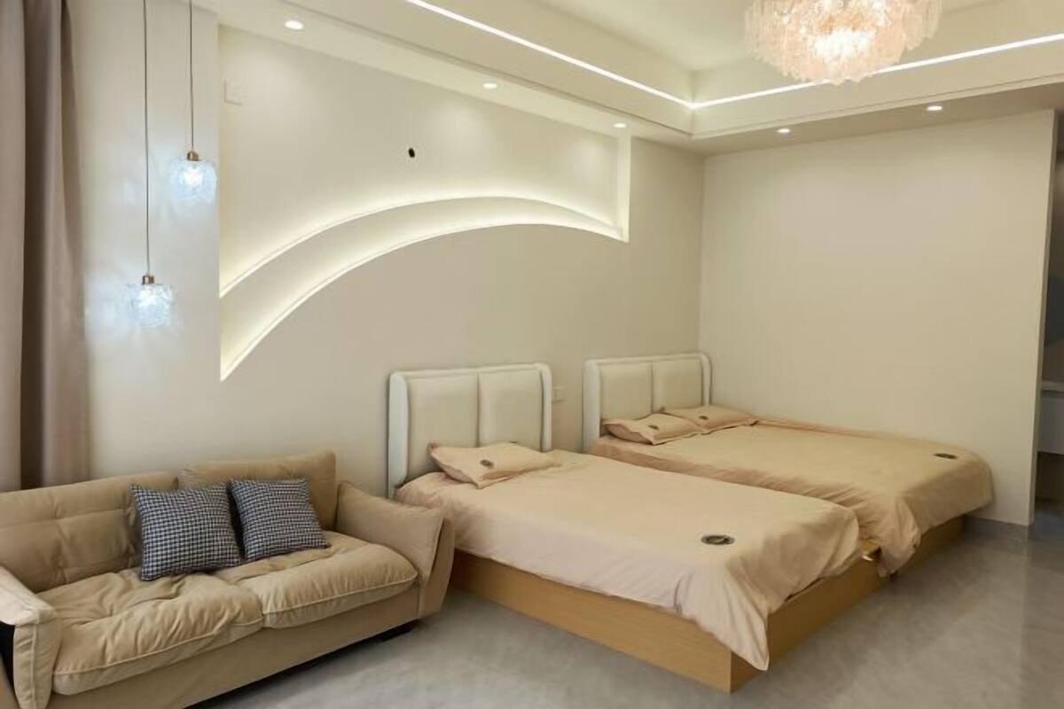 A bedroom with two beds, a sofa, and a chandelier.