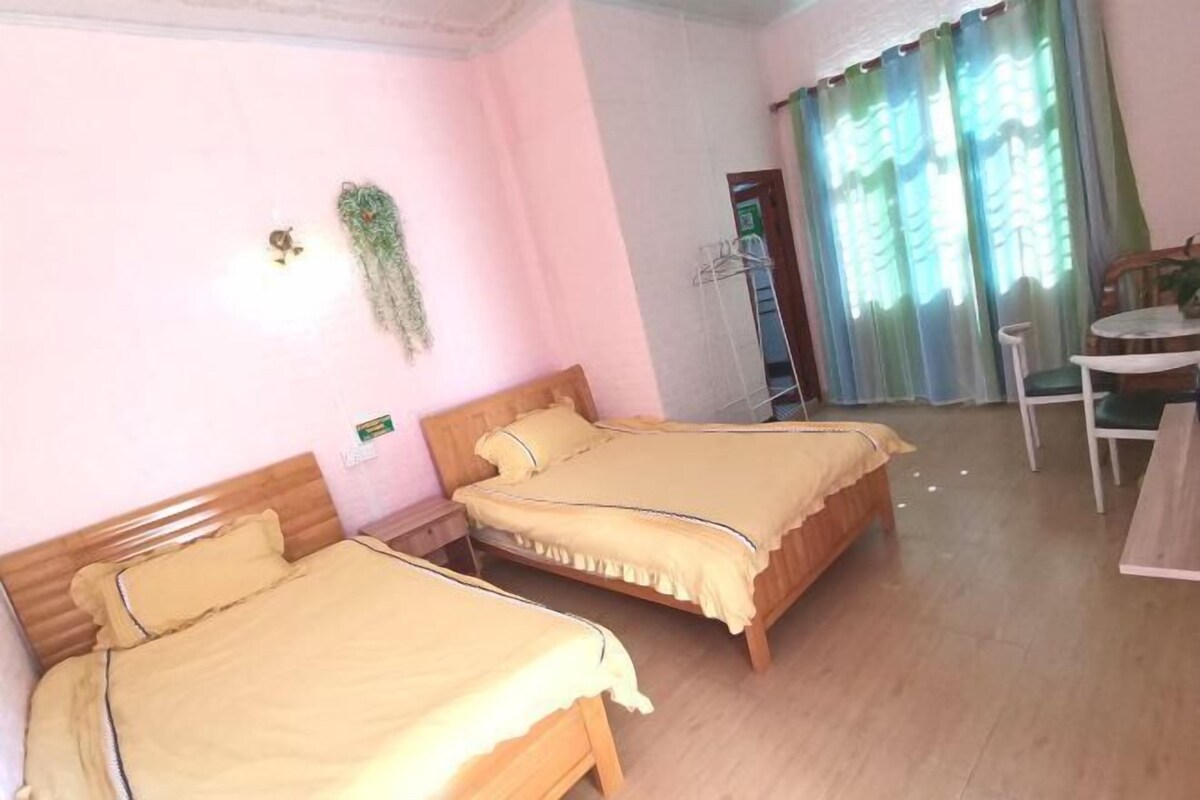 Ein Hotelzimmer mit zwei Betten, einem kleinen Tisch, einem Stuhl und einem Fenster mit Vorhängen.