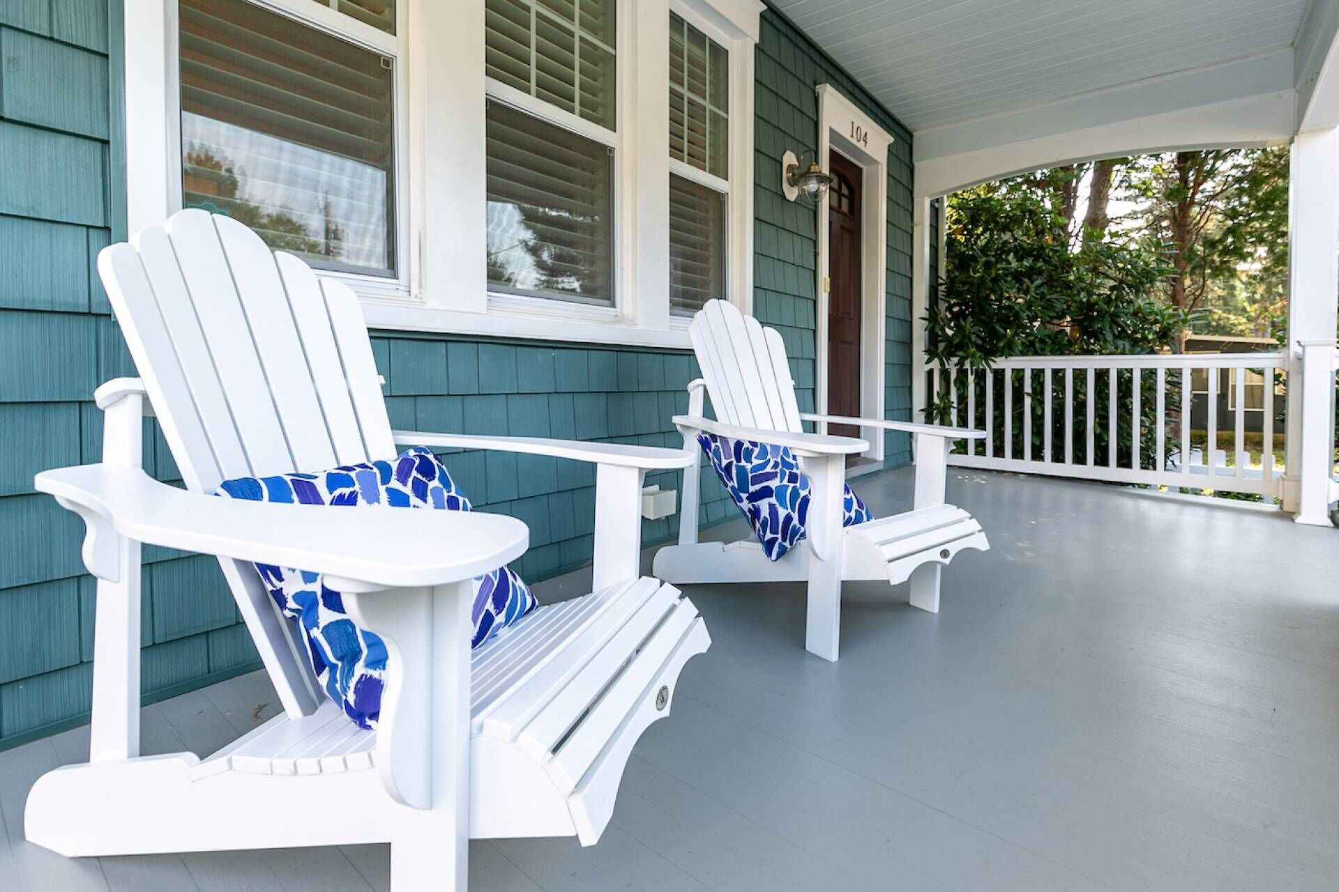 Une véranda avec deux fauteuils Adirondack et une petite table.