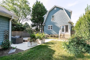 A residential house with a sloped roof, a front porch, and a well-maintained lawn.