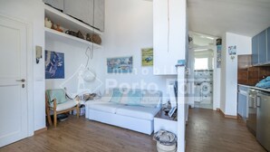 Amplia sala de estar con sofá, mesa de comedor y área de cocina con armarios y electrodomésticos.