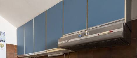 A kitchen with blue cabinets and a stainless steel range hood.