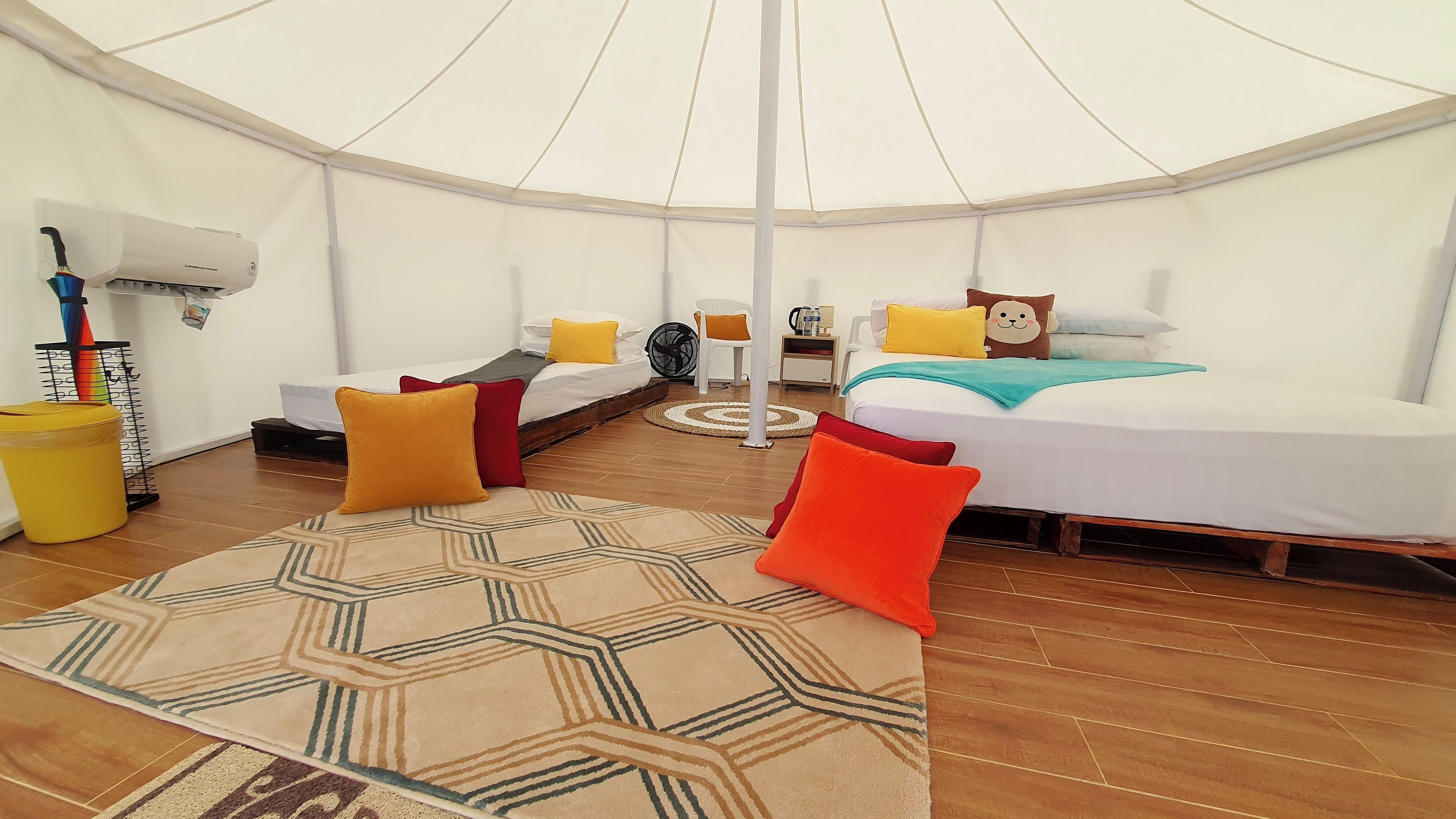 A spacious tent with two beds, a fan, and a yoga mat.