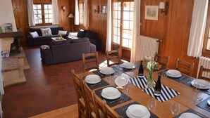 A wooden interior with a dining table set for four, a sofa, and a fireplace.