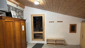 A room with a wooden cabinet, a door with a window, a small bench, and a coat rack.