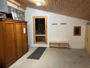 A room with a wooden cabinet, a door with a window, a small bench, and a coat rack.