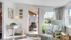 A cozy room with a large window, a comfortable chair, a small table, and a decorative lamp. - "Sveina" - 600m from the sea by Interhome (Hadsund)