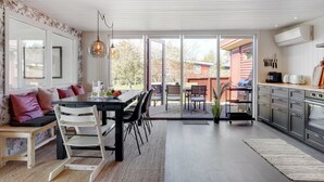 A modern kitchen with a dining area, large windows, and a view of the backyard. - "Sveina" - 600m from the sea by Interhome (Hadsund)