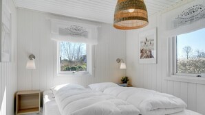 A bedroom with a large bed, two bedside lamps, a bedside table, and a window with a view of trees. - "Sveina" - 600m from the sea by Interhome (Hadsund)