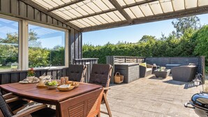 Eine Terrasse im Freien mit einem Holztisch, Stühlen und einem Grill.