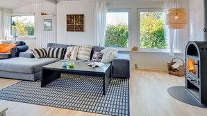 Ein modernes Wohnzimmer mit einer Eckcouch, einem Couchtisch und einem Kaminofen.