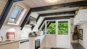 Una cocina con tragaluz, armarios blancos, horno empotrado y ventana con vistas a vegetación.