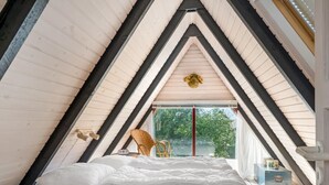 Un dormitorio acogedor en el ático con una cama, una silla y una pequeña mesa.