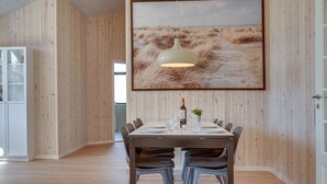 A dining area with a wooden wall, a large painting, and a table set for six with chairs. - "Bentine" - 1.6km from the sea by Interhome (Saltum)