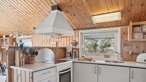 Una cocina moderna con paredes de madera, una estufa blanca y una ventana con vista a árboles.