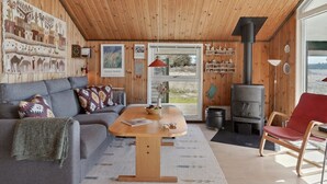 Una sala de estar acogedora con techo de madera, un sofá, una mesa de centro y una chimenea.