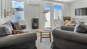 Una sala moderna con chimenea, dos sofás, una mesa de centro y un televisor.