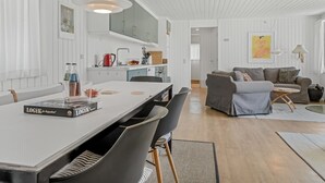 Una cocina moderna con armarios blancos, una mesa de comedor con sillas y una isla de cocina.