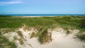 Un paisaje costero con dunas, una playa y el océano.