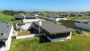 Parque moderno de caravanas con múltiples unidades que presentan techos planos y diseños compactos, con vistas a colinas verdes y cielos despejados.