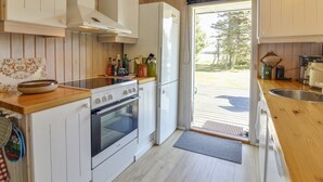 Eine moderne Küche mit weißen Schränken, einer Holz Arbeitsplatte, einem eingebauten Backofen und einem großen Fenster.