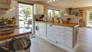 Eine kompakte Küche mit Holzausstattung, einer integrierten Waschmaschine und einer Arbeitsplatte aus Holz.