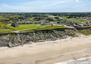 Vista aérea de una zona costera con edificios residenciales, una playa y un acantilado.