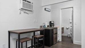 Eine kleine Küche mit integriertem Kühlschrank, einer Kaffeemaschine und einem Spülbecken.