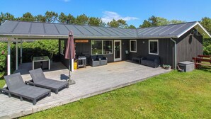 Eine moderne Außenpatio mit Lounge-Möbeln, einem Grillbereich und einer überdachten Sitzgelegenheit.