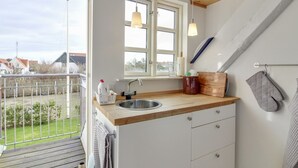 A kitchen with a wooden countertop, a sink, and a window. There is a towel hanging on the door handle, and a wooden cutting board on the countertop. - "Evangelina" - 350m from the sea by Interhome (Løkken)
