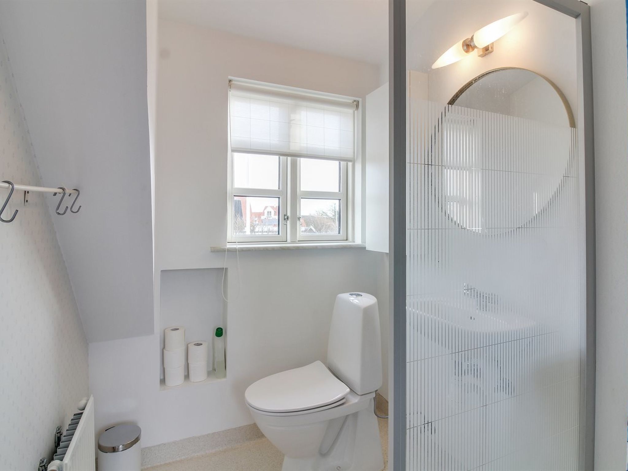 Et moderne badeværelse med toilet, et vindue og en bruseniche.