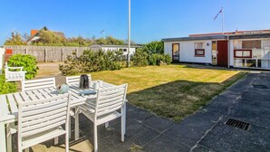 A residential area with a white house, a flagpole, and a patio with a table and chairs. - "Evangelina" - 350m from the sea by Interhome (Løkken)